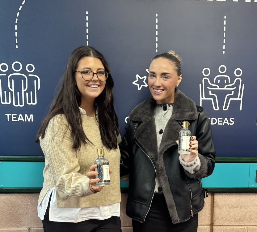 Two business management students holding skincare products.
