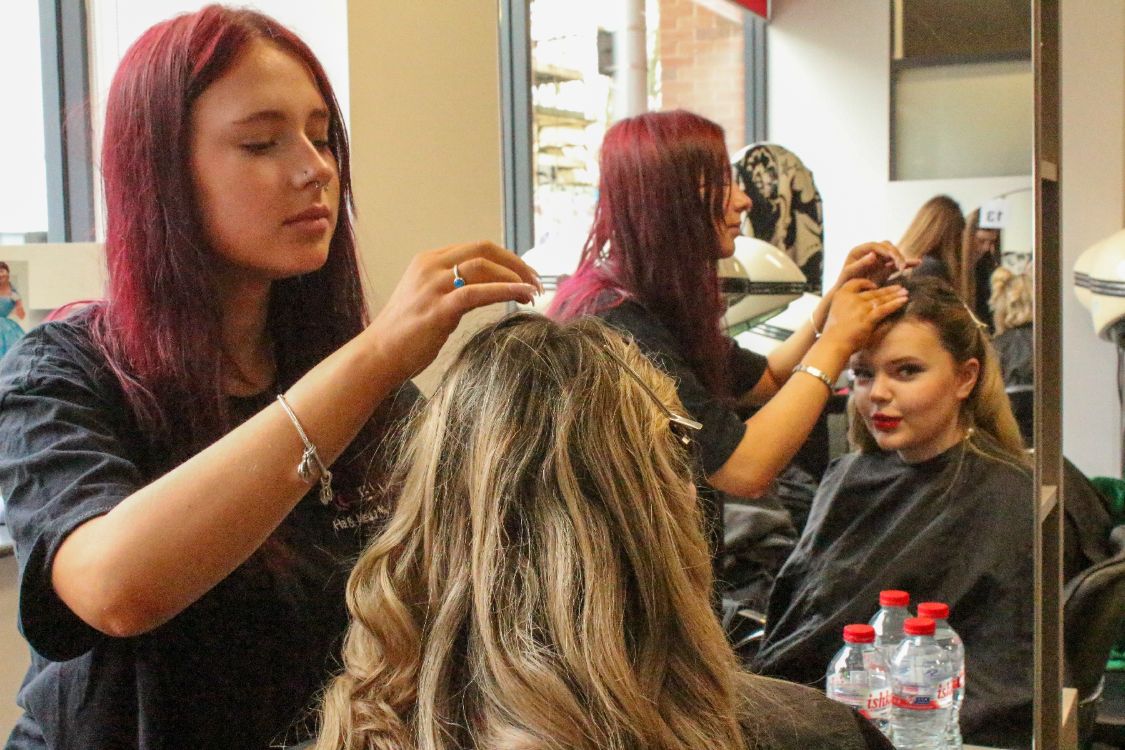 Picture of a hair and media student working on their model