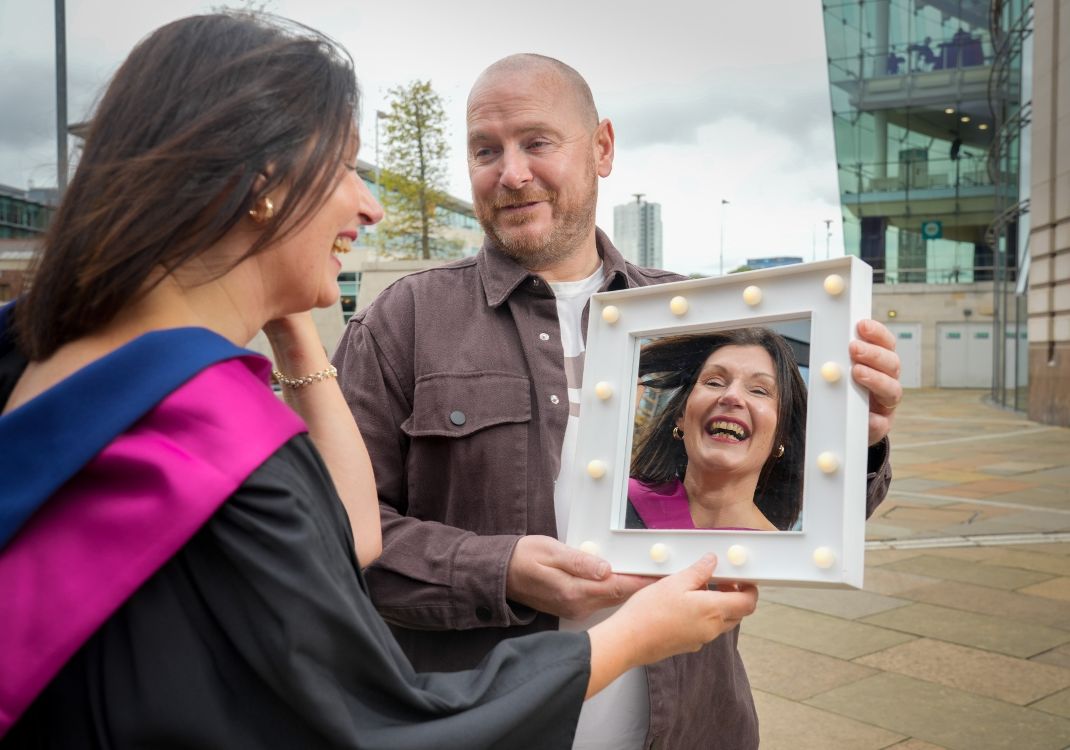Graduate with reflection in mirror with husband