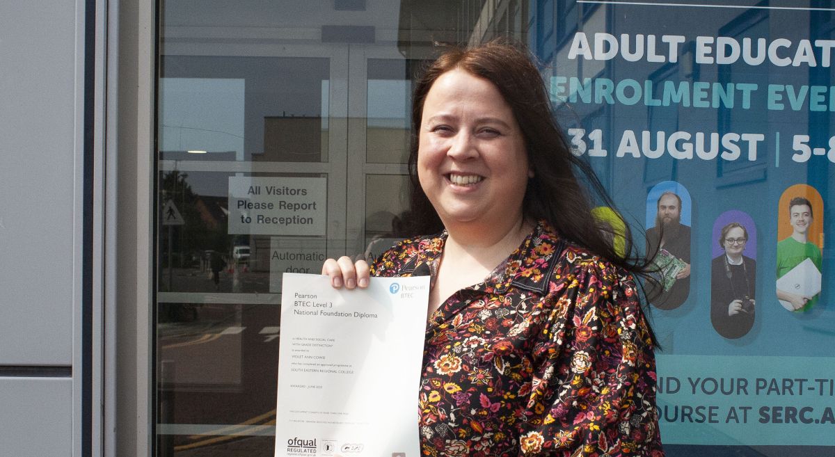 Female student holding results certificate and smiling to camera