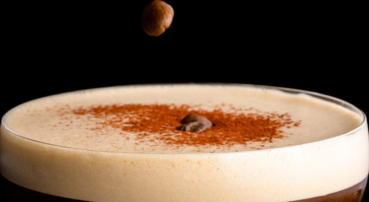 Coffee bean mid air dropping into frothy coffee